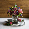 Bouquet of flowers in a pebbled glass vase on a wooden surface
