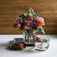 Bouquet of flowers in a pebbled glass vase on a wooden surface