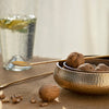 Bowl of walnuts with a glass of water and lemon slices on a textured surface